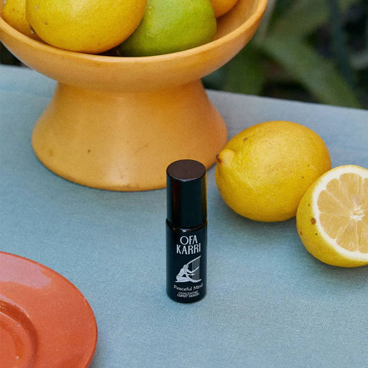 Aromatherapie Roll-On neben Zitronen und Obstschale auf hellblauem Tisch