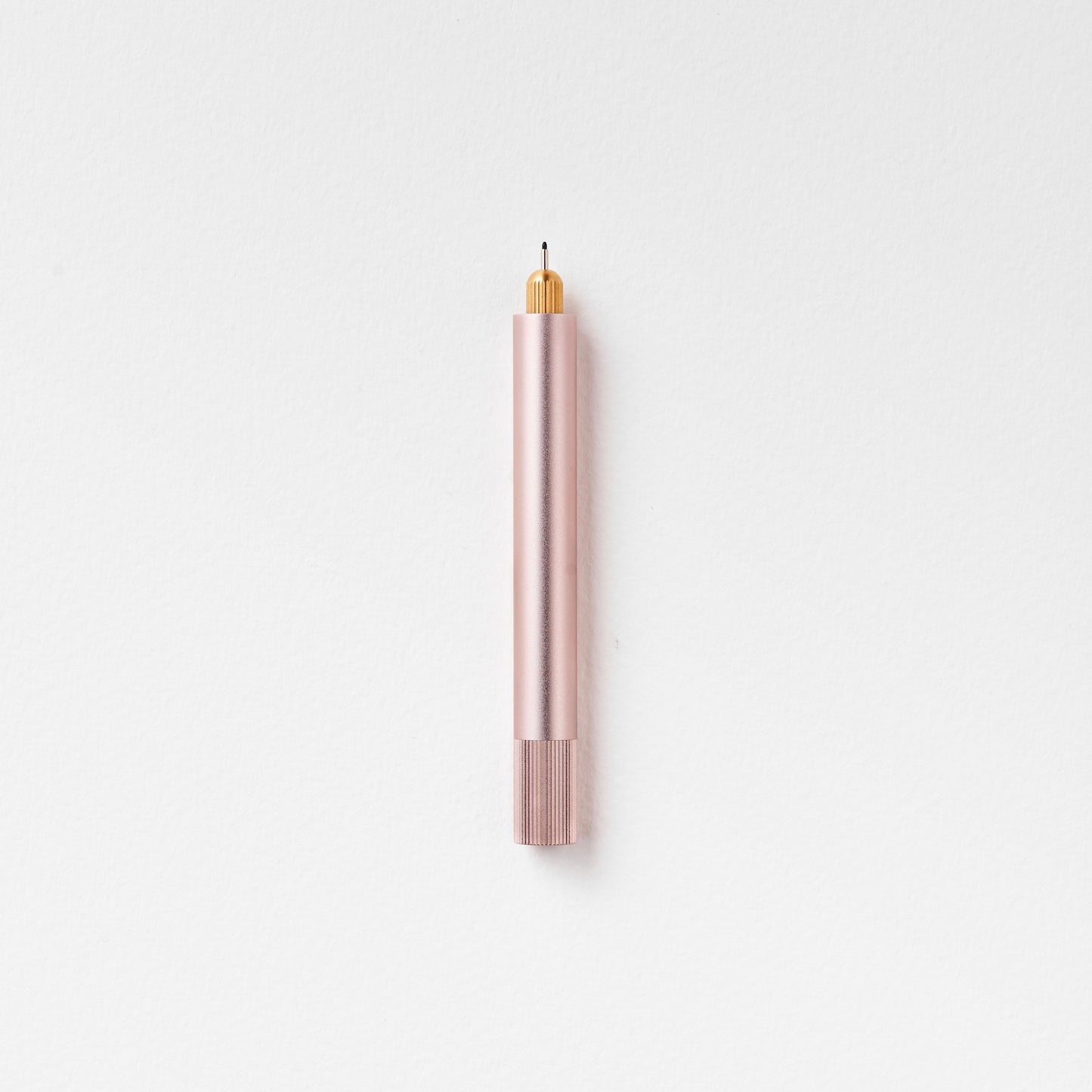 Minimalistischer Stift in Rosé mit goldener Spitze auf weißem Hintergrund, modernes Design