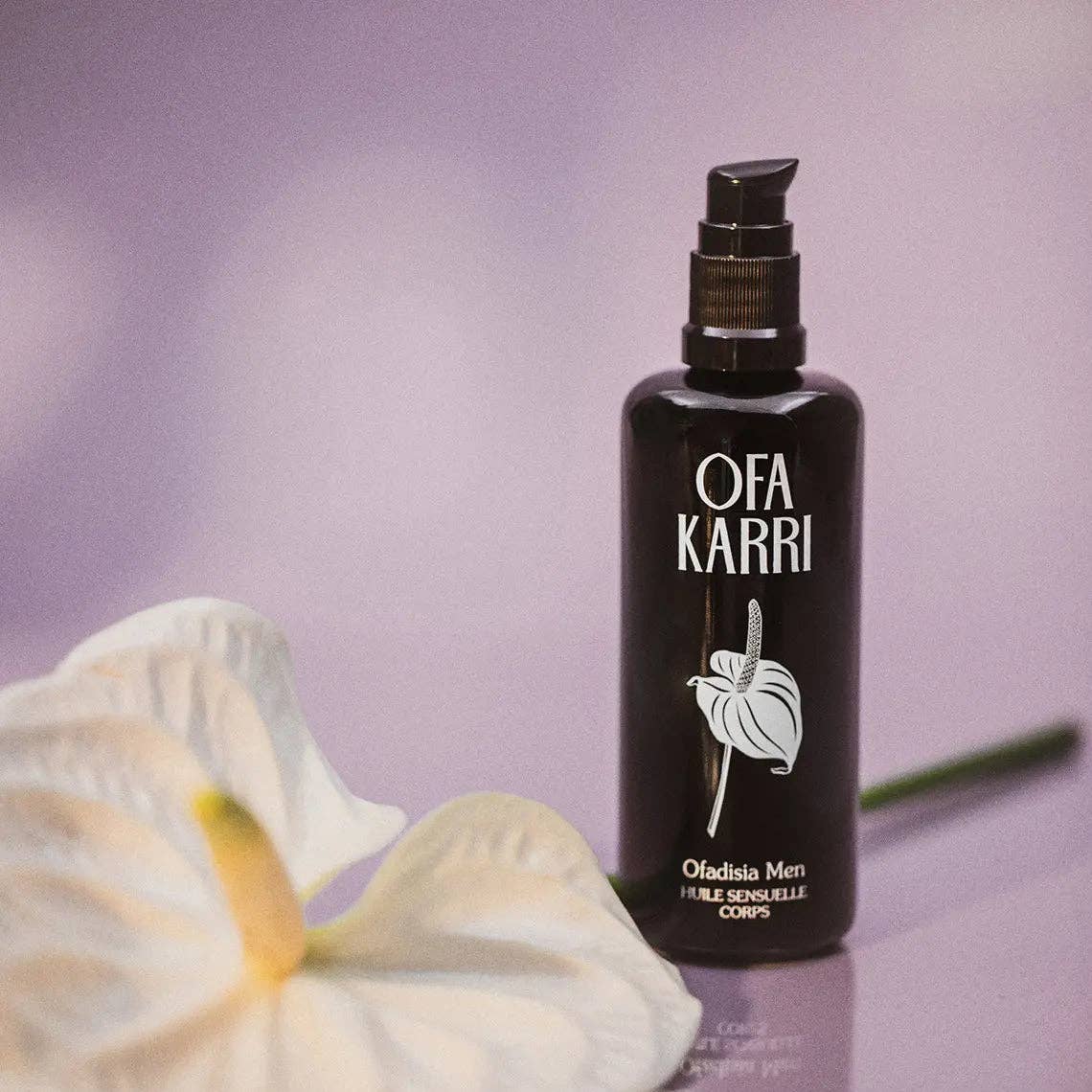 Schwarze Körperölflasche mit Pumpverschluss, Blume vorne, lila Hintergrund, Wellnessprodukt
