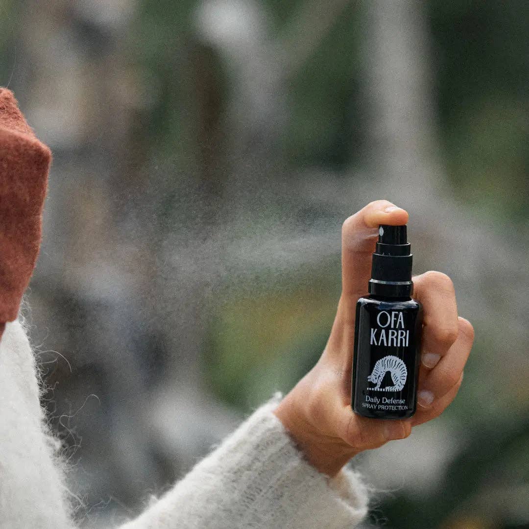 Hand sprüht Ofa Karri Daily Defense Spray im Freien, Naturhintergrund, Wellness Produkt