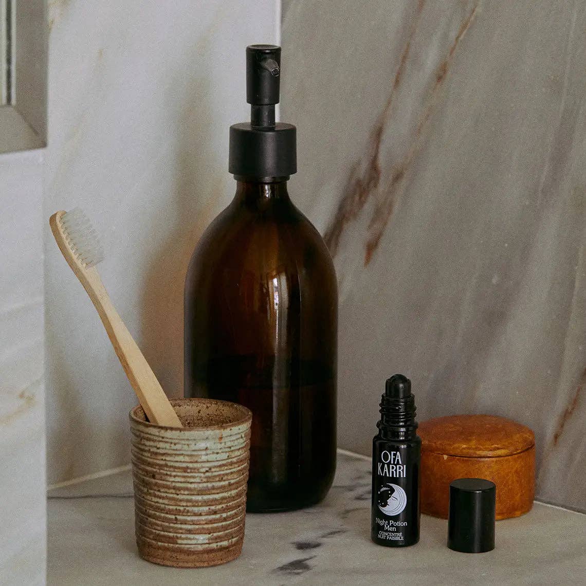 Braune Glasflasche mit Pumpe, Holz-Zahnbürste im Becher und Naturkosmetik im Bad