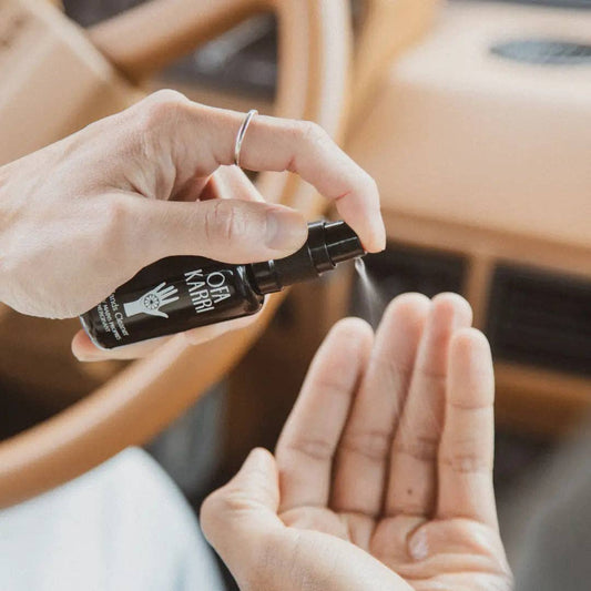 Hand sprüht Ofa Karri Handreiniger aus Flasche im Auto, natürliche Pflege