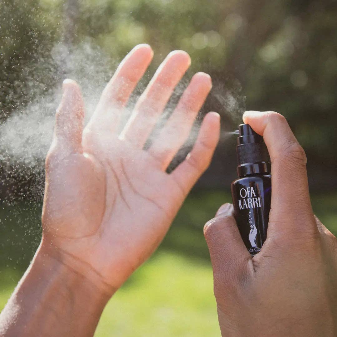 Hand sprüht mit Ofa Karri Spray auf offene Handfläche im Sonnenlicht, Naturhintergrund