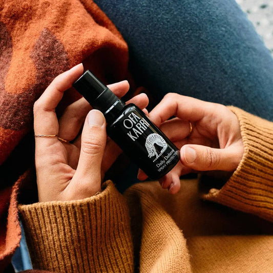 Frau hält Ofa Karri Spray in der Hand, gemütliche Kleidung, Entspannung, Naturprodukt