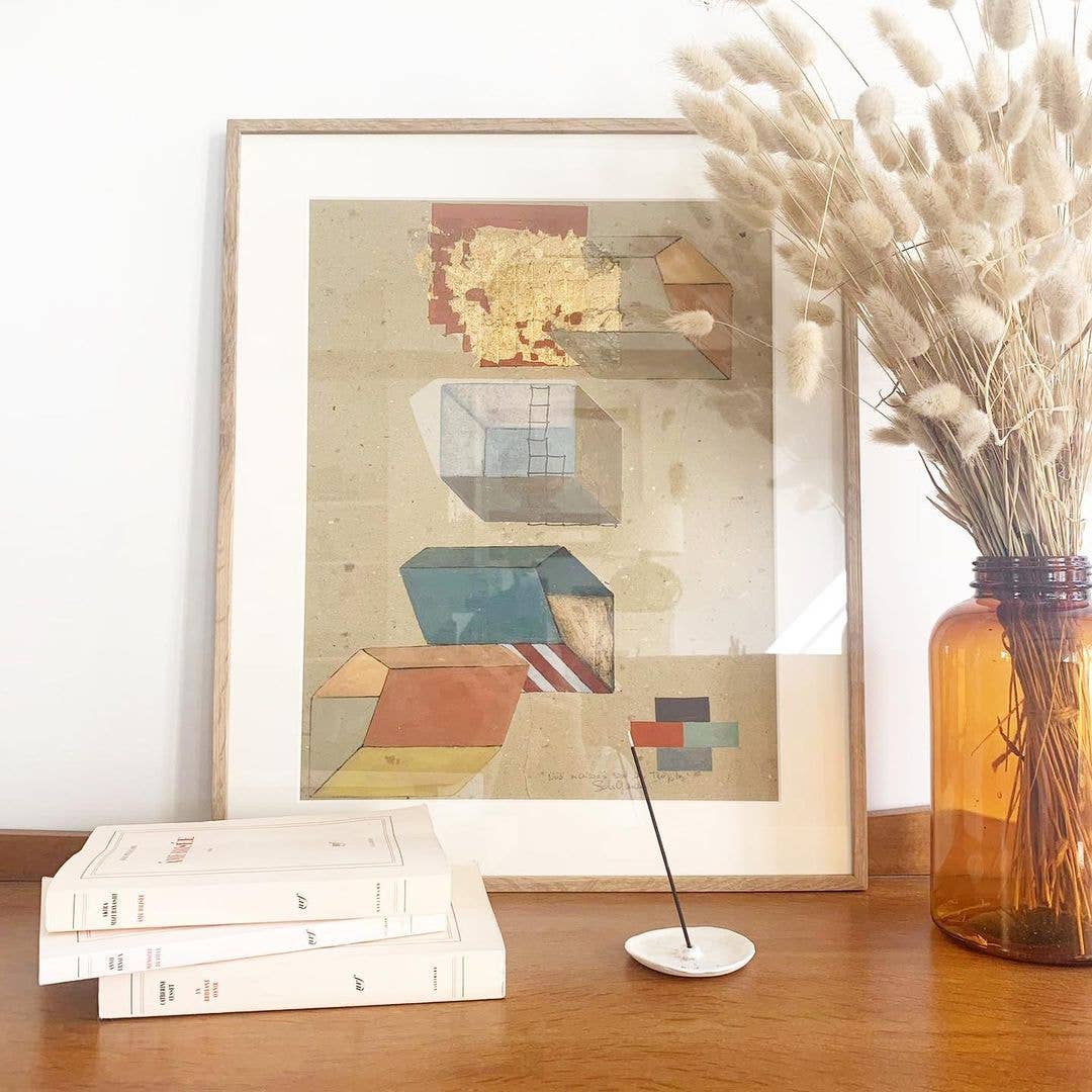 Minimalistisches Stillleben mit abstraktem Kunstdruck, Trockenblumen in brauner Vase, Büchern und Räucherstäbchen auf Holzoberfläche