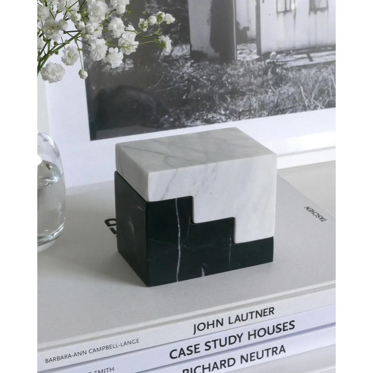 Zwei geometrische Buchstützen aus weißem und schwarzem Marmor auf Büchern, modernes Design
