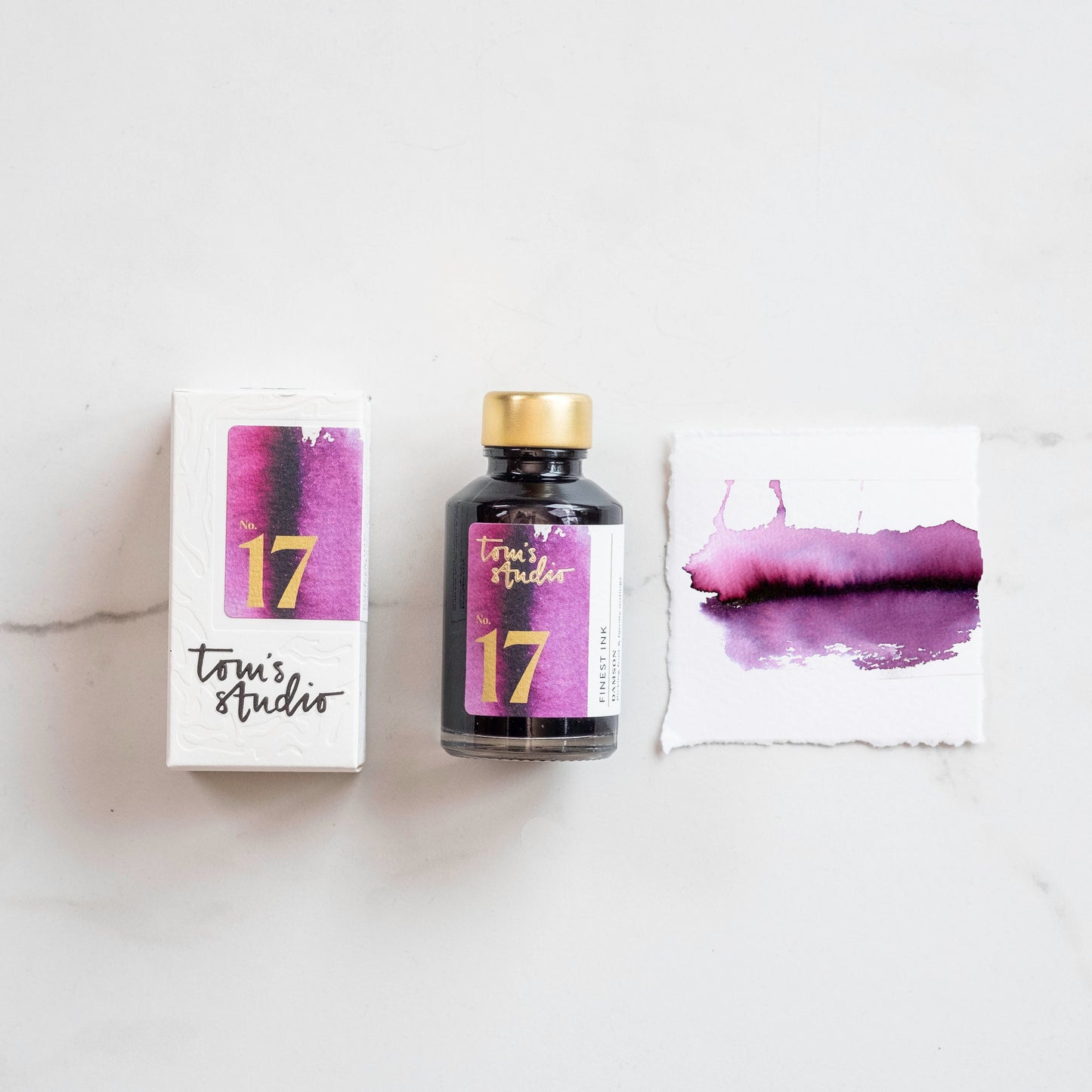 Lila Füller-Tinte in Glasflasche und Verpackung mit Farbbeispiel auf Papier, Flachlay
