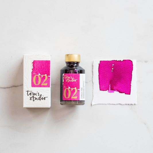 Glas mit Füller-Tinte in Himbeerrosa neben passender Verpackung und Farbmuster auf Papier
