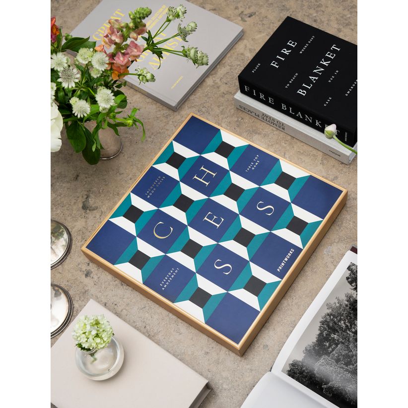 Schachspiel mit modernem geometrischem Design auf Tisch, umgeben von Büchern und Blumenvasen