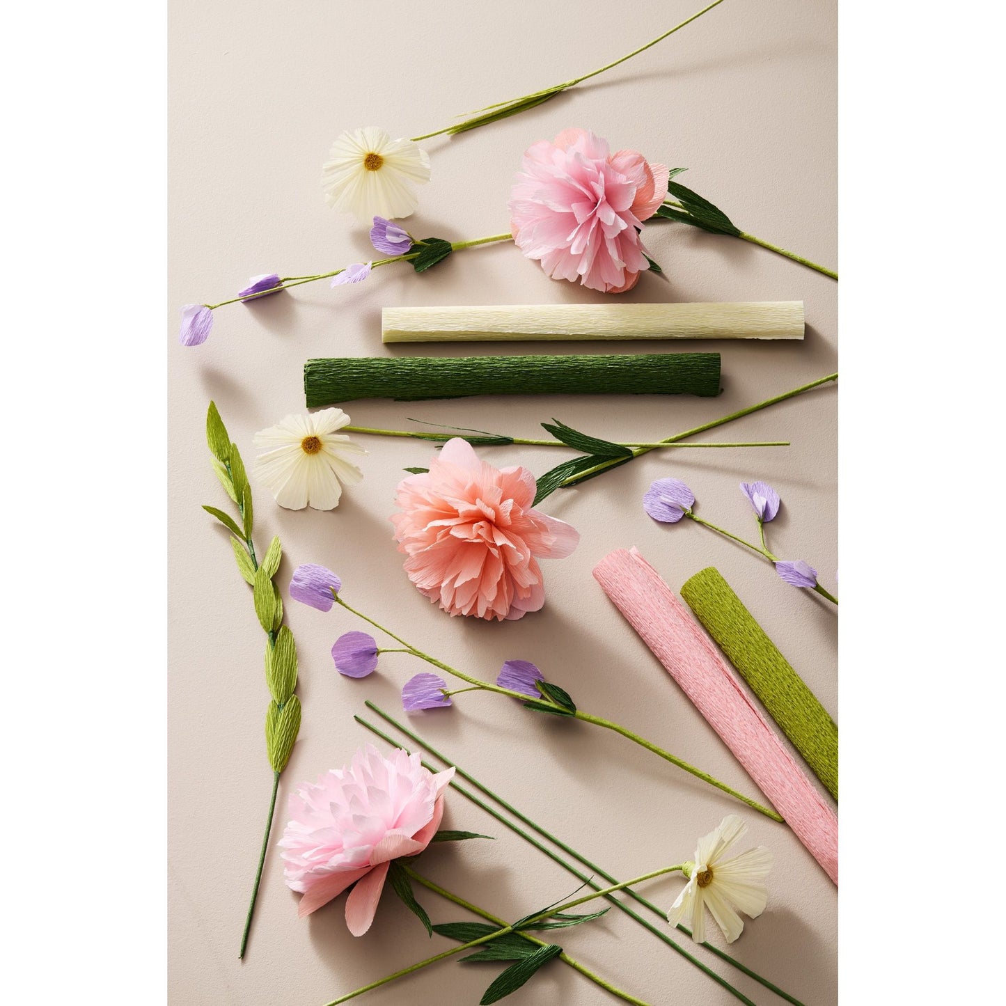 Papierblumen und Krepppapier in Pastellfarben flach auf hellem Untergrund arrangiert