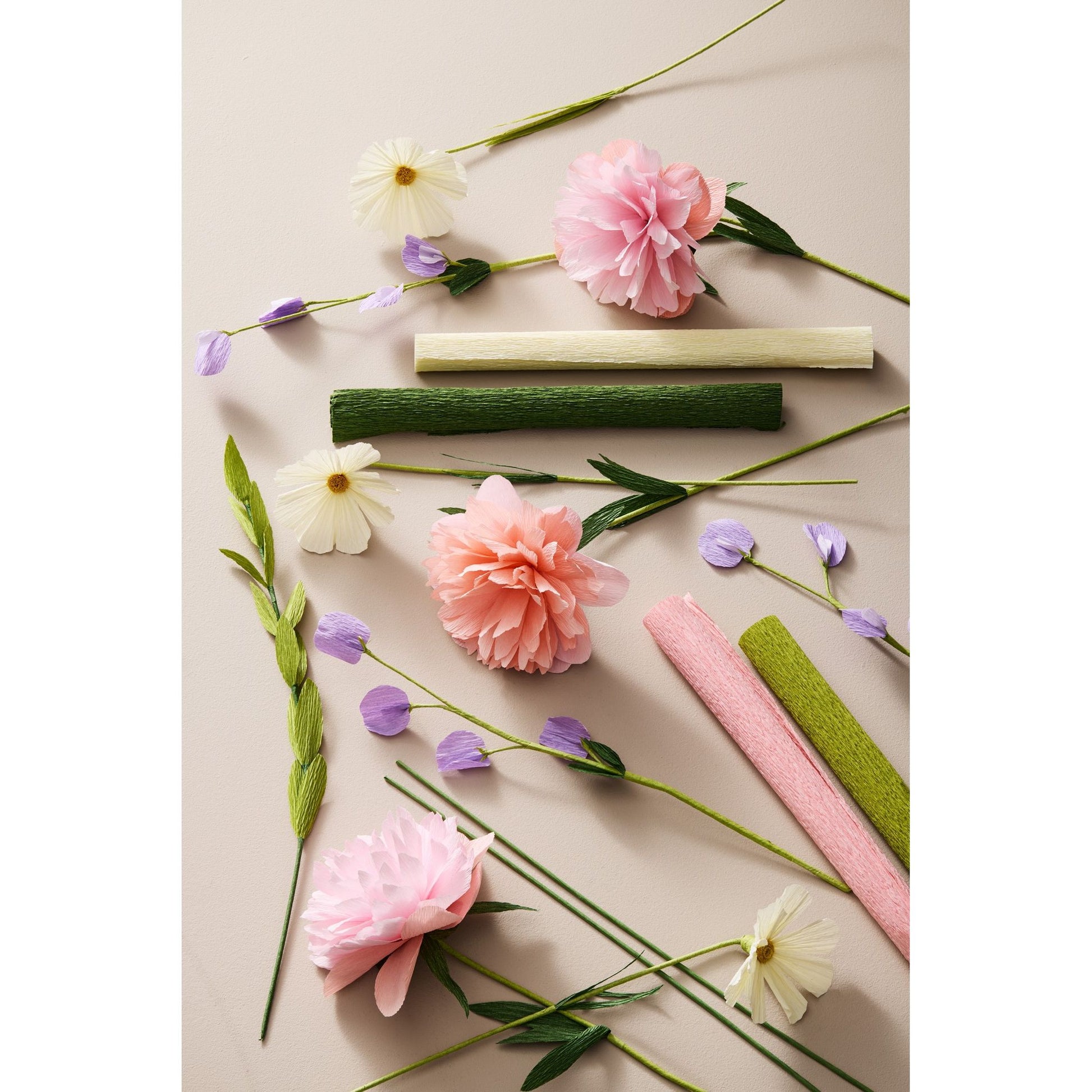Papierblumen und Krepppapier in Pastellfarben flach auf hellem Untergrund arrangiert