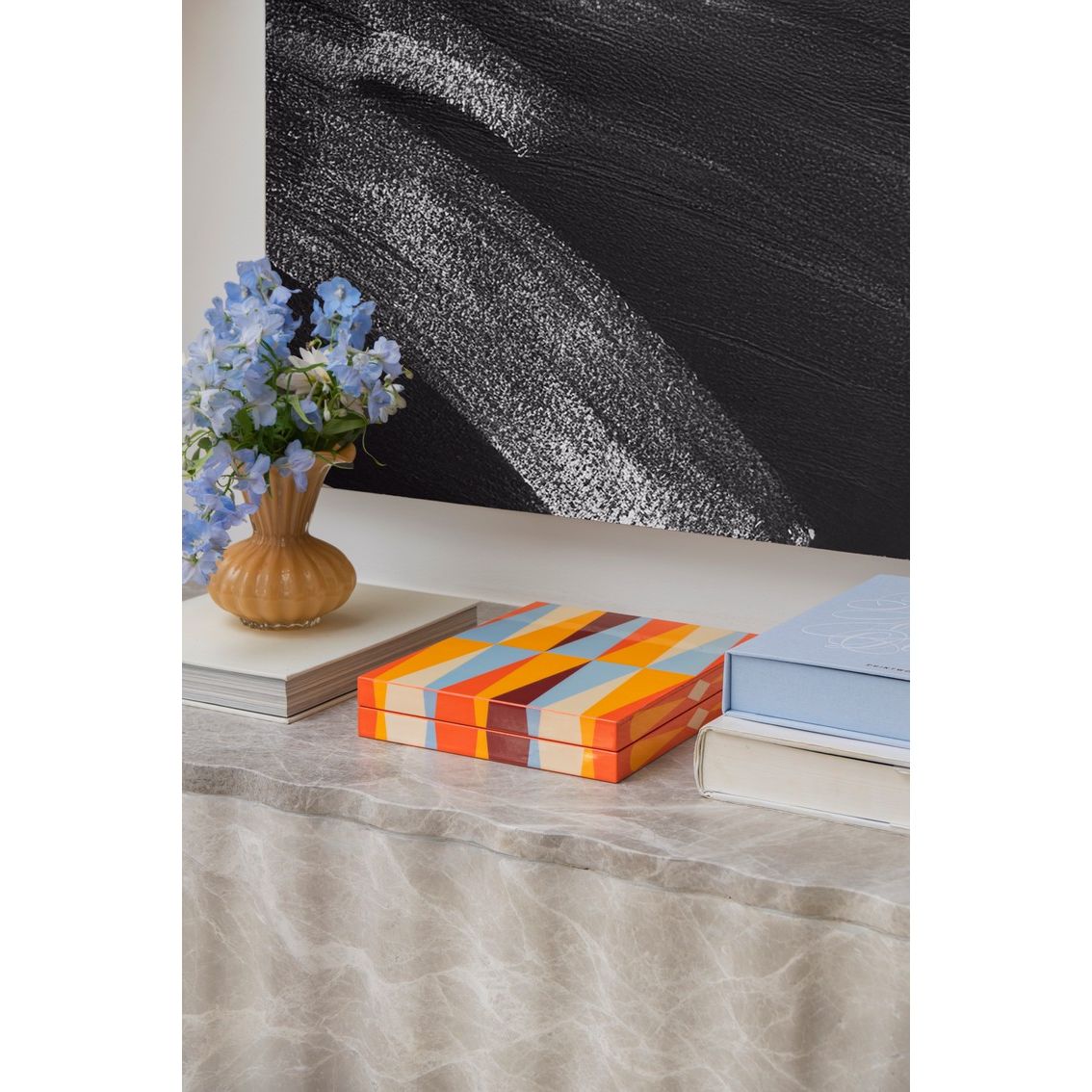 Bunter Spielekarton auf Tisch mit Blumen in Vase und Büchern, modernes Wohnzimmer-Design