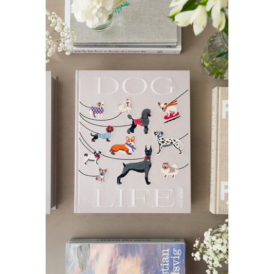 Stilvolles Coffee Table Buch mit Hunden auf hellgrauem Cover, dekorativ arrangiert mit Blumen und weiteren Büchern.