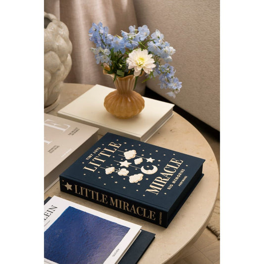 Stilvoll arrangierter Couchtisch mit Blumen in Vase, Design-Büchern und Notizbuch