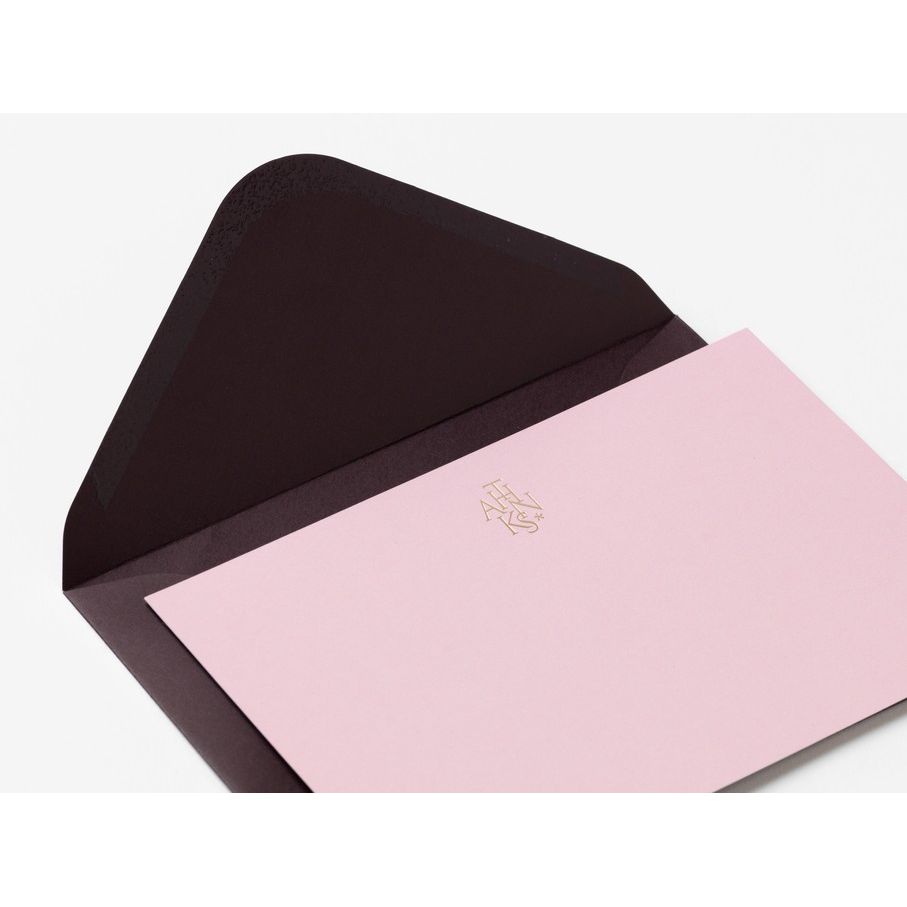 Offener schwarzer Umschlag mit rosa Karte und goldener Prägung, minimalistisches Design