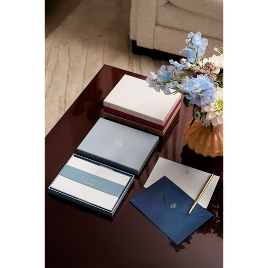 Elegantes Schreibset mit Briefpapier, Umschlägen und Kugelschreiber auf Tisch neben Vase mit Blumen