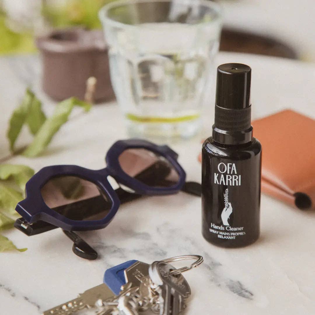 Handreinigungsspray, Sonnenbrille, Schlüssel und Geldbörse auf einem Marmortisch