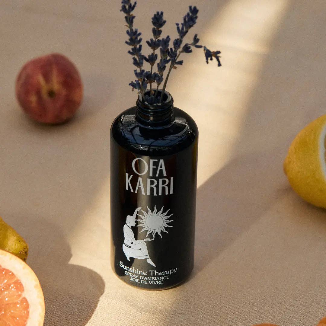 Schwarze Flasche Raumduft mit Lavendel, umgeben von Zitrone, Grapefruit und Pfirsich