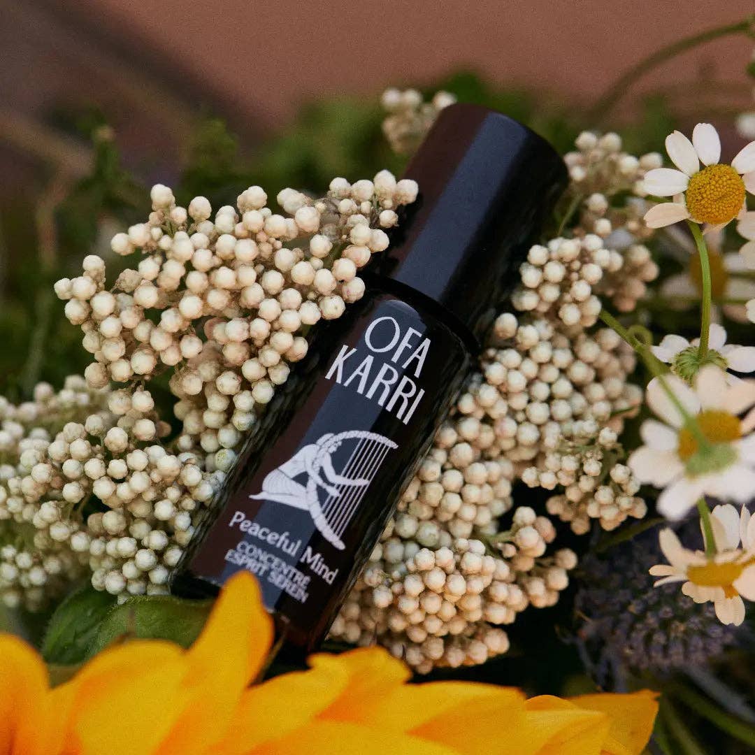 Aromatherapie-Roll-On Fläschchen mit Aufschrift 'Peaceful Mind' auf Blumen liegend, Naturkosmetik Produkt