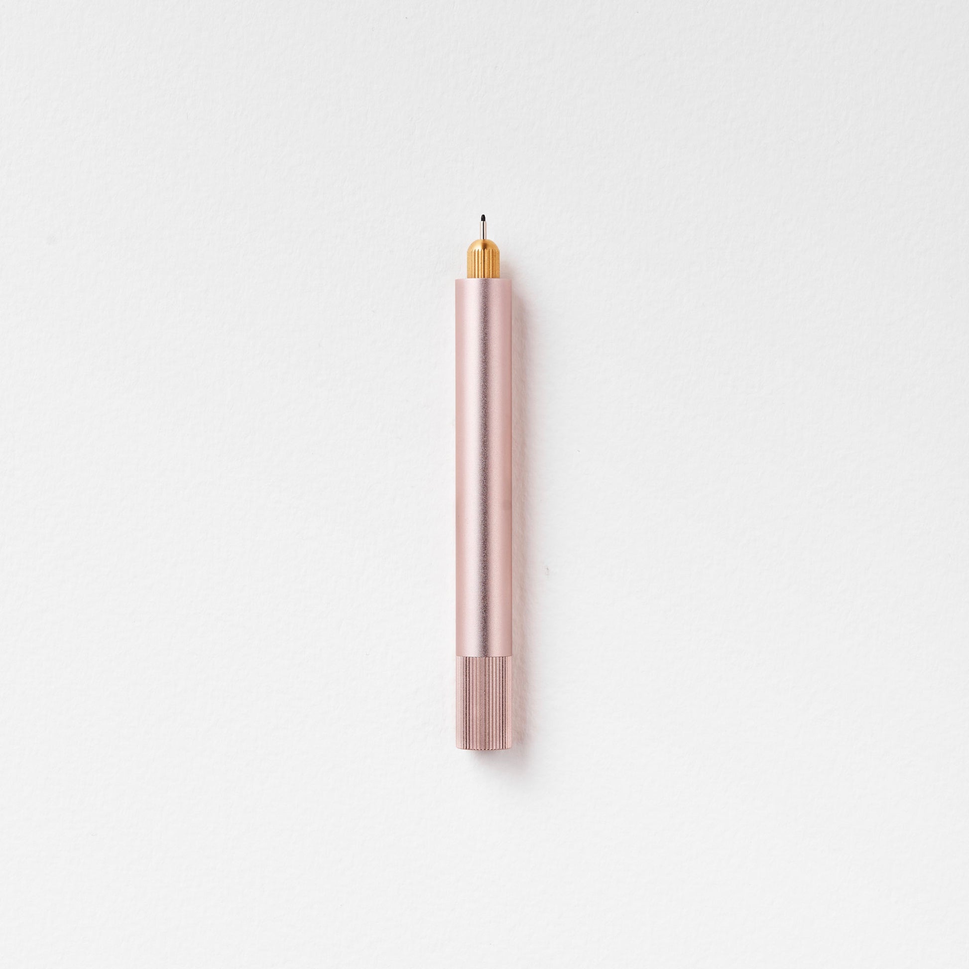 Minimalistischer Stift in Rosé mit goldener Spitze auf weißem Hintergrund, modernes Design