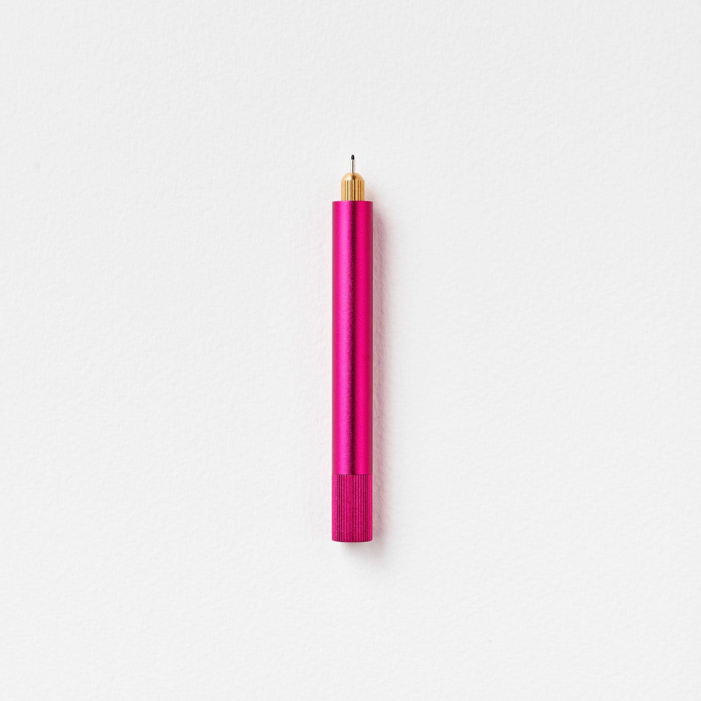 Minimalistischer Stift aus Metall in Pink mit goldener Spitze auf weißem Hintergrund