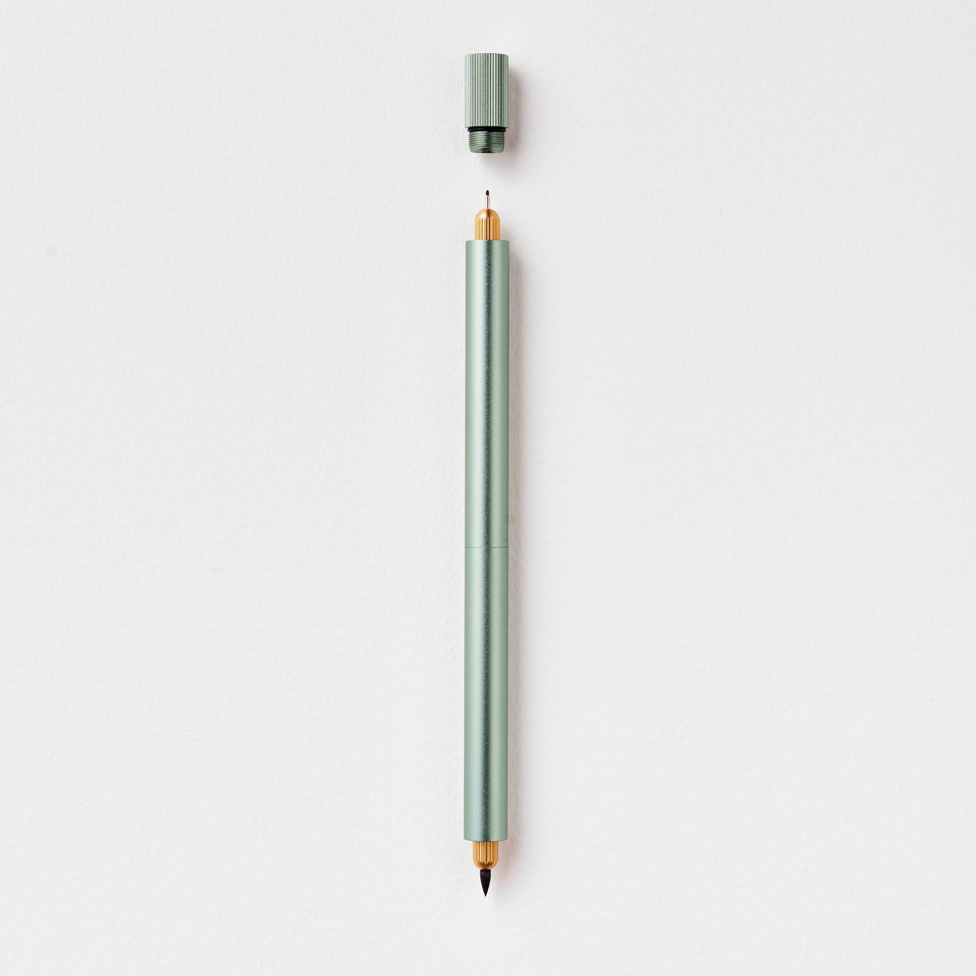 Minimalistischer Duo-Stift in Salbeigrün mit abgenommenem Deckel auf weißem Hintergrund