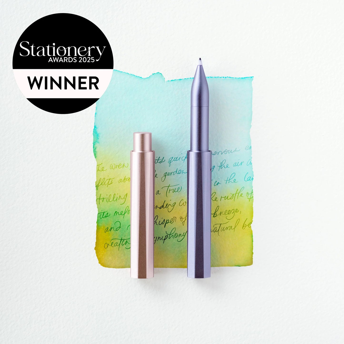 Design-Kugelschreiber aus Metall, lila und rosé, vor Aquarell mit Handschrift, Stationery Award 2025